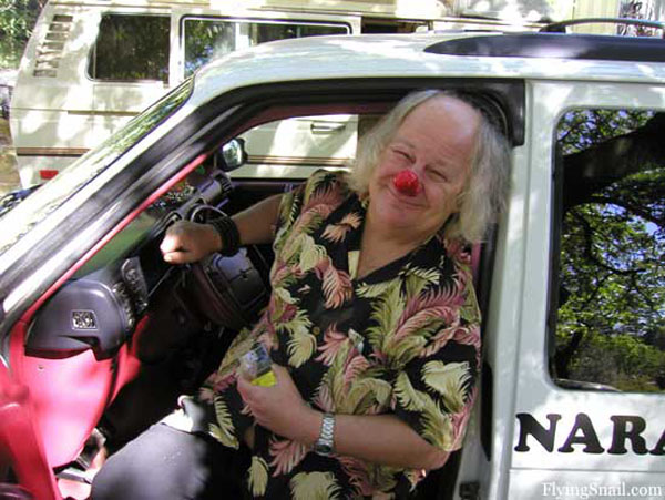 Photograph of Wavy Gravy with a red clown nose on, getting out of his 'Clownmobile' truck.