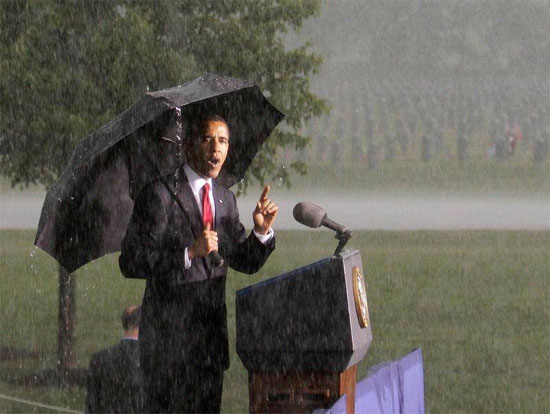 Obama, with cemetery in background, shows what a real President looks like, standing in the rain